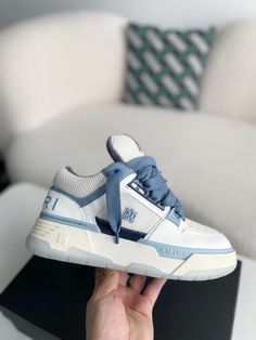 Embrace the spirit of rebellious luxury with these AMIRI MA-1-inspired sneakers in a crisp white and blue colorway. Crafted with a blend of premium leather and breathable mesh, these high-top sneakers capture the essence of AMIRI's signature aesthetic. The bold silhouette, featuring an exaggerated sole and signature details like the AMIRI logo on the side and tongue, exudes confidence and individuality. Experience the perfect fusion of comfort, quality, and head-turning style. Luxury High-top Sneakers With Perforations For Streetwear, Luxury High-top Sneakers With Boost Midsole For Sports, Blue Leather High-top Sneakers With Perforations, Blue Perforated Sneakers For Streetwear, Blue Sneakers With Perforations For Streetwear, Luxury High-top Sneakers For Streetwear With White Sole, Luxury High-top Sneakers With White Sole For Streetwear, Luxury High-top Custom Sneakers With Translucent Outsole, Luxury Custom High-top Sneakers With Translucent Outsole