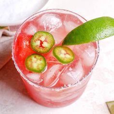 a pink drink with lime slices on the rim and green garnish in it