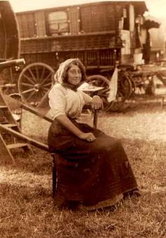 an old photo of a woman sitting on a chair in front of a horse drawn wagon