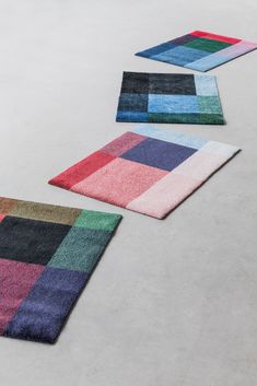 three different colored rugs laying on the floor next to each other in an empty room