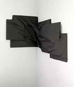 an abstract piece of art with black cloth on it's back and white walls