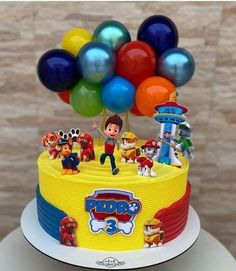 a birthday cake decorated with cartoon characters and balloons