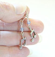 a person holding onto some kind of musical note charm with crystal beads on it's end