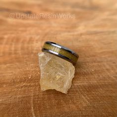 a ring sitting on top of a wooden table next to a piece of wood and a rock