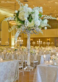 the centerpieces in this ballroom are adorned with white flowers and candles for an elegant touch