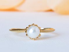 a close up of a ring with a pearl in the center on a white surface