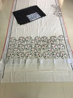 a white table cloth with black and red designs on it, sitting on top of a tile floor