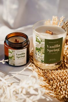 a candle sitting on top of a bed next to a jar of vanilla spring candles