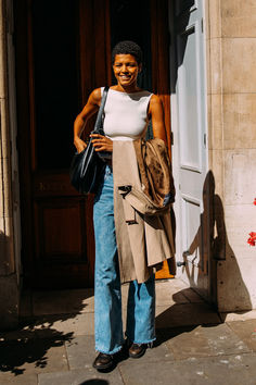 a woman standing in front of a door with her hand on her hip and smiling