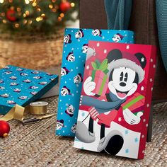 two mickey mouse christmas cards sitting next to a christmas tree