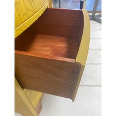 a close up of a wooden drawer on a white tile floor with yellow and brown furniture