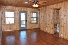 an empty room with wood paneling and ceiling fan