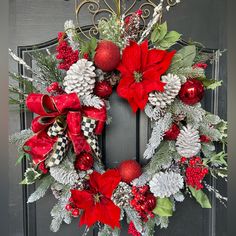 a christmas wreath with pine cones, poinsettis and other decorations on a door