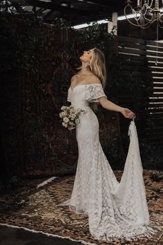 a woman in a white wedding dress standing on a rug with her back to the camera