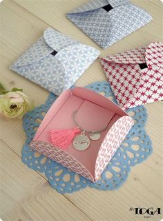 four different colored envelopes sitting on top of a doily next to a flower