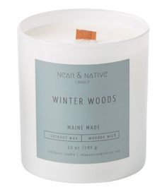 a white candle with a wooden stick in it that says winter woods on the front