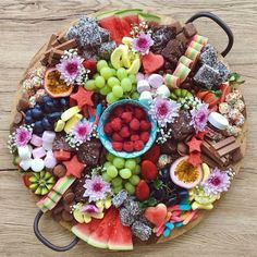 a platter filled with lots of different types of fruit and chocolates on top of a wooden table