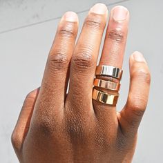 a woman's hand with three different rings on her fingers and one ring in the middle