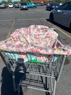 a shopping cart covered with a pink flowered cover on the side of a road