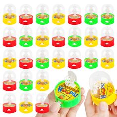 a hand holding a small plastic toy in front of many different colored cups and lids