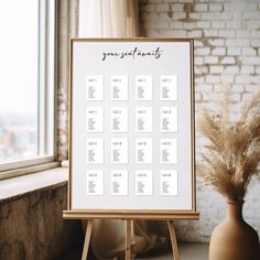 an easel with a seating chart on it in front of a window