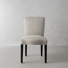 a beige chair sitting in front of a white wall