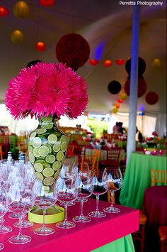 a vase filled with pink flowers sitting on top of a table covered in wine glasses