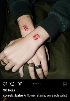 two people holding hands with tattoos on their arms and the words love written in red ink