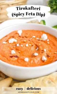 a white bowl filled with red dip surrounded by pita chips and broccoli