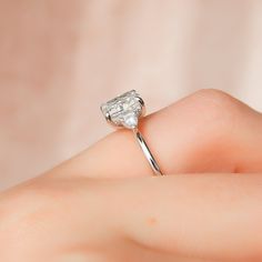 a woman's hand holding an engagement ring with a diamond in the middle, on top of her finger