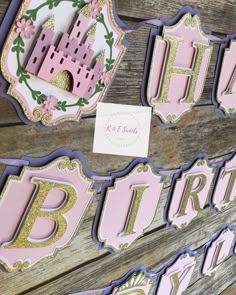 pink and gold princess birthday party decorations on wooden planks with paper cutouts that spell out the word happy birthday