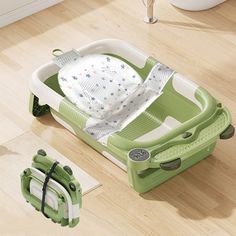 a green and white baby bath tub sitting on top of a wooden floor