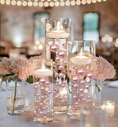 the centerpieces are filled with pink flowers and lit candles for a wedding reception