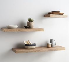 two wooden shelves with bowls and cups on them