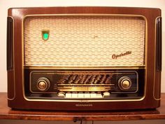 an old fashioned radio sitting on top of a wooden table next to a white wall