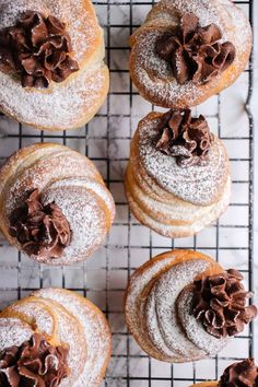 several powdered donuts with chocolate frosting on a cooling rack