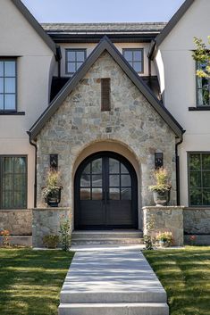 the front entrance to a large house with stone and black trim on it's windows