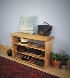 a wooden shelf with shoes and purses on it next to a rug in a room