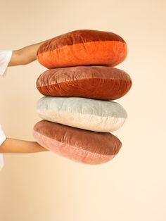 a person holding four pillows in the shape of three different colored sausages on top of each other