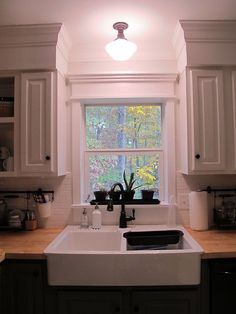 a white kitchen sink sitting under a window