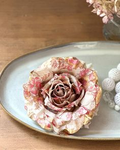 a flower sitting on top of a metal tray next to beads and flowers in a vase