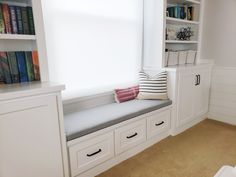 a window seat with bookshelves and pillows in the corner, next to a bookcase