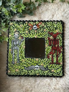 a decorative photo frame decorated with skeletons and flowers