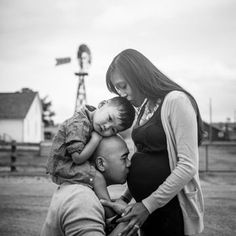 a black and white photo of a woman holding a baby boy while he kisses him