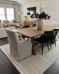 a table with chairs and a vase on top of it in a room filled with furniture