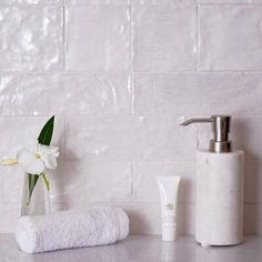 a bathroom counter with white towels, soap dispenser and flowers on it