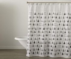 a shower curtain with black and white christmas trees on it, hanging in front of a bathtub