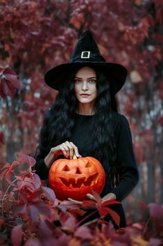 a woman dressed as a witch holding a pumpkin