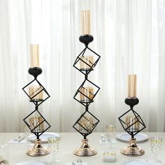 two black candlesticks sitting on top of a table next to plates and silverware