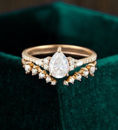 a diamond ring sitting on top of a green velvet cushioned box with gold trimmings